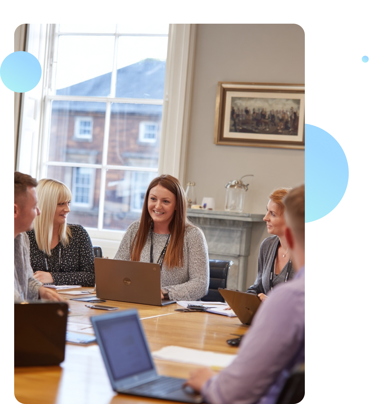 A team of social work professionals in an open-plan office, focused on computers and paperwork, working collaboratively.