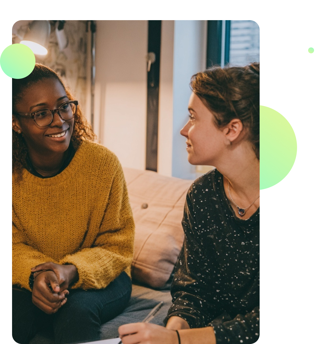 A support worker and young person talking together in a relaxed shared living space, both smiling and comfortable.