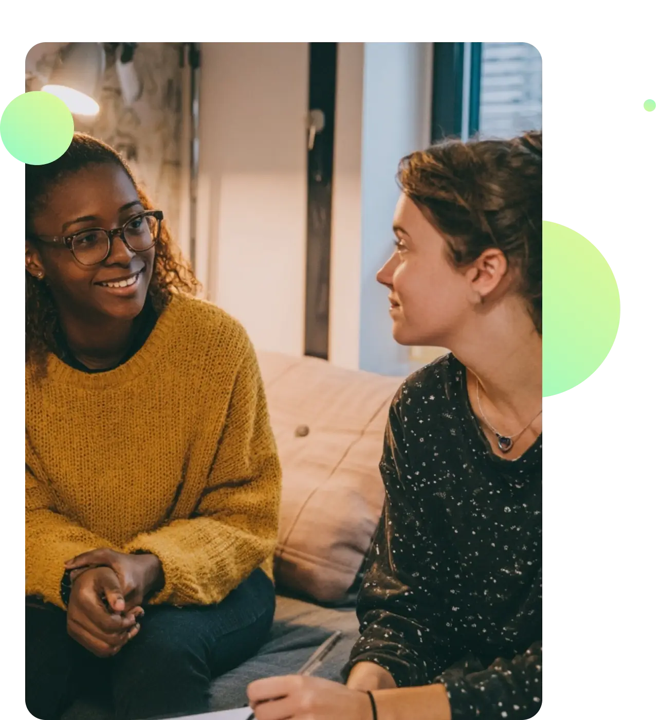 A support worker and young person talking together in a relaxed shared living space.